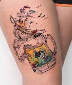 a woman's thigh with a beer mug and ship tattoo on the side of her leg