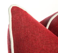 a red pillow with white piping on it