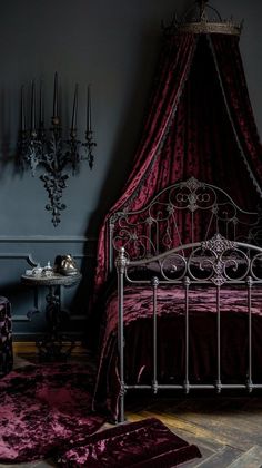 a bed with a canopy and purple bedspread in a dark room next to a table