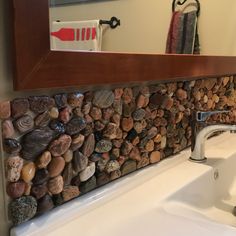 a bathroom sink sitting under a mirror covered in rocks