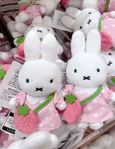 two white stuffed rabbits in pink dresses with green leaves on their ears, sitting next to each other