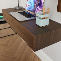 an open laptop computer sitting on top of a wooden desk next to a box of pencils