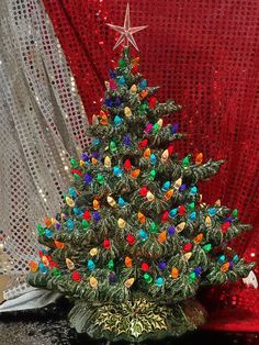 a small christmas tree sitting on top of a table next to a red cloth covered wall