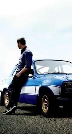 a man sitting on the hood of a blue car