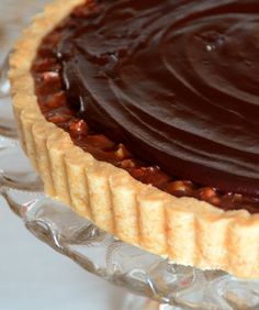 there is a chocolate pie on the glass platter, ready to be cut into pieces