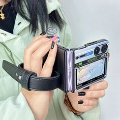 a woman is holding her cell phone in one hand and looking at the screen with both hands