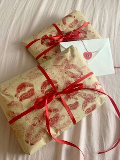 two wrapped presents with red ribbon on white sheets