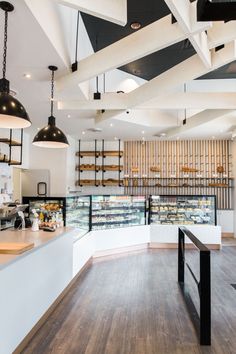 the inside of a bakery with lots of food on shelves and lights hanging from the ceiling