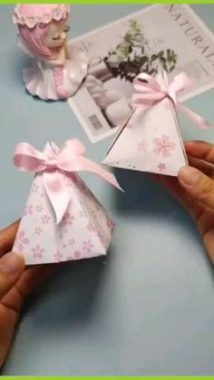 someone is holding an origami box with a pink ribbon around it and another toy next to it