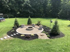 an outdoor fire pit surrounded by trees and landscaping