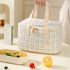 a person holding a white bag next to a bowl of pasta and an orange slice