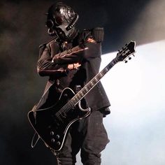 a man wearing a gas mask and holding a guitar