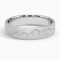 a white gold wedding band with mountains in the middle and a mountain range engraved on it