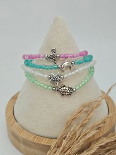 three bracelets with charms on top of a wooden stand