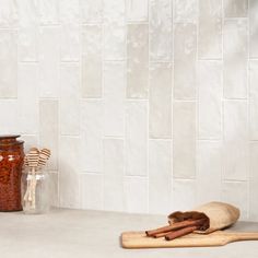 cinnamon sticks and spices are sitting on the counter in front of a white tiled wall