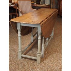 an old wooden table with two chairs in the back and one chair on the side