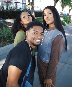 three people posing for the camera on a sidewalk