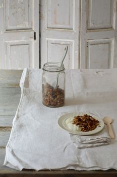 a table topped with a plate of food next to a jar filled with granola