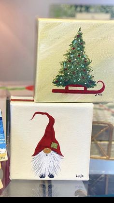 three canvases with christmas paintings on them are sitting on a glass table in front of a lamp