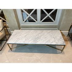 a white marble coffee table sitting on top of a tiled floor next to two chairs