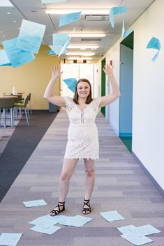 a woman is standing on the floor with paper airplanes in the air above her head