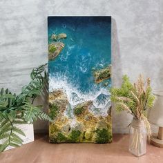 an aerial view of the ocean with rocks and green plants in vases next to it