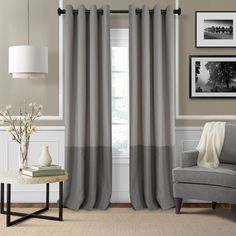 a living room with grey and white curtains on the windowsills, a gray chair and a coffee table in front of a window