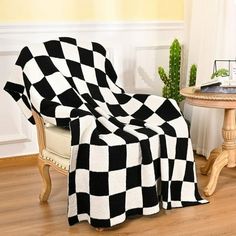 a black and white checkered blanket sitting on top of a chair next to a table