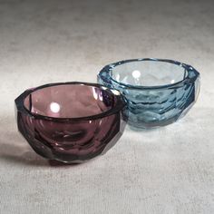 two glass bowls sitting next to each other on top of a white cloth covered floor