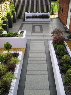 an outdoor garden with benches and plants on the sides, along with wooden decking