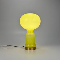 a yellow lamp sitting on top of a table next to a charger and plugged in