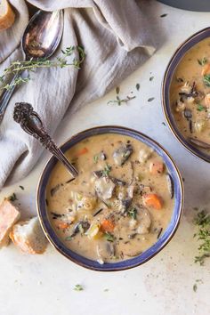 two bowls filled with soup next to some bread