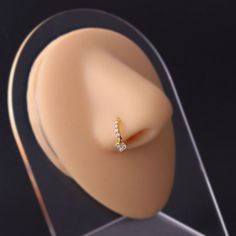 a gold ring with three small diamonds on it's side, in front of a clear acrylic display case