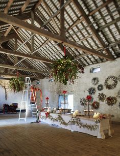 a table with wreaths and candles on it in a room that looks like an old barn