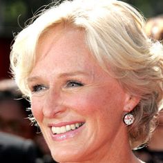 an older woman with blonde hair smiling at the camera and wearing earrings on her head