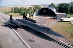 an airplane is parked on the side of the road near a man walking down the street