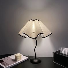 a lamp that is on top of a table next to a book and some other items