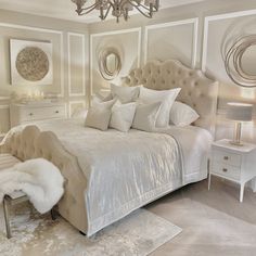 a large white bed sitting in a bedroom next to a chandelier and two nightstands