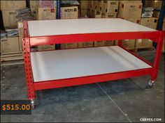 a red and white shelf sitting on top of a pallet in a room filled with boxes