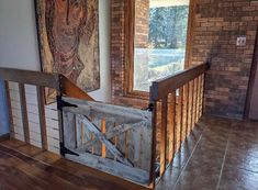 a wooden gate in front of a brick wall with a painting hanging on the wall