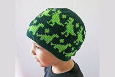 a young boy wearing a green and black knitted beanie hat with shamrocks on it