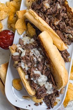 two sandwiches and chips on a plate with ketchup