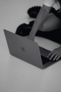 a woman is sitting on the floor with her laptop in front of her, while she sits down