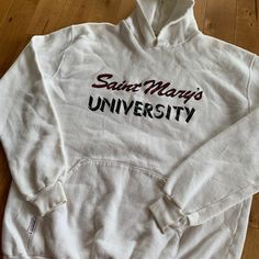 "This piece is a vintage hooded sweatshirt from the 1990s for Saint Mary's University in Halifax, Nova Scotia, Canada.  -Made in Canada, Monsport -55% Cotton, 45% Polyester -No Major Stains, Yellowing, or Flaws Tag Size: XL, fits slightly smaller *refer to measurements for true fit* Pit to Pit: 22.5\" Length: 28\" Please also assess the photos and measurements carefully using your own personal judgement as we do not accept returns. Keep in mind that this is a piece of vintage clothing that may hold a residual scent from its past. While we wash all of the clothing we sell (except for certain items which are steam cleaned) we cannot guarantee that we have been able to remove all of the stubborn scents. Buyers should be prepared for the possibility of having to wash the items again once they Vintage Hoodie With Double-lined Hood For Sports, College Cotton Sweatshirt With Double-lined Hood, Cotton Sweatshirt With Double-lined Hood For College, Cotton Double-lined Hood Sweatshirt For College, Collegiate Cotton Hoodie For Campus, Collegiate Style Hoodie Sweatshirt With Logo Print, Collegiate Logo Print Hoodie Sweatshirt, Collegiate Hoodie Sweatshirt With Logo Print, Vintage Fleece Hoodie With Drawstring Hood