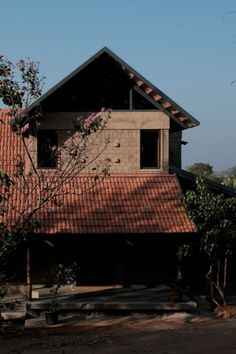 a house with a red tile roof next to trees