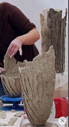 a woman is making vases out of clay