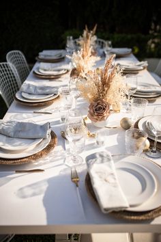 the table is set with white plates and place settings