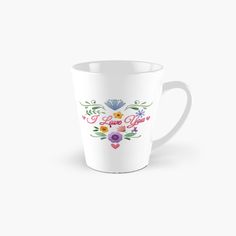 a tall white mug with flowers and the words i love you in red, yellow, blue