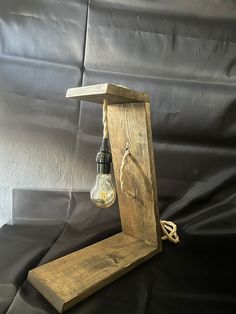 an old fashioned light bulb is in a wooden box on a black cloth covered background