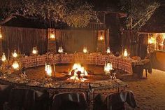 an outdoor fire pit surrounded by chairs and tables with candles lit up in the middle